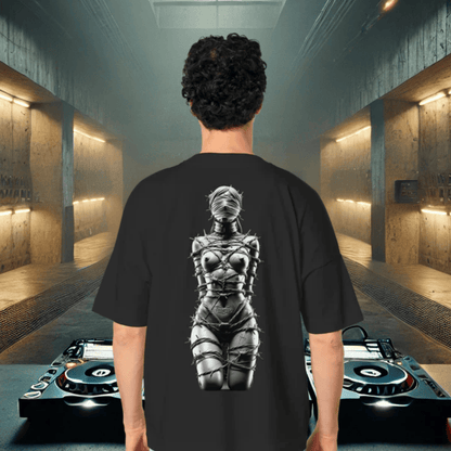 Person in schwarzem BDSM Techno Fusion T-Shirt mit Stacheldraht-Design auf der Rückseite, DJ-Decks im Hintergrund.